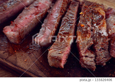 medium rare, sliced rib eye steak, grilled cowboy steak, on a chopping board, close-up, homemade, top view, no people, 133826406