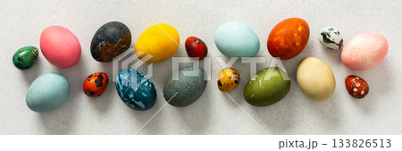 Various Easter eggs in vibrant colors and patterns are neatly arranged, showcasing the joy and creativity associated with spring celebrations and family gatherings, banner 133826513