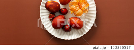 Colorful eggs are arranged on a plate alongside a small bowl of onion skins, how to dye eggs brown, creating a festive atmosphere for an Easter gathering at home, banner Colorful eggs are arranged on a plate alongside a small bowl of onion skins, how to dye eggs brown, creating a festive atmosphere for an Easter gathering at home, banner 133826517