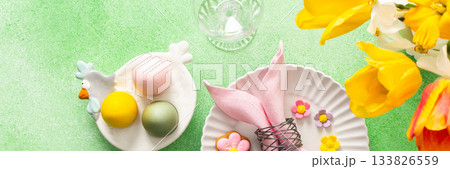 A beautifully arranged Easter table setting showcases a decorative egg nestled in a pink napkin, surrounded by a glass of water and fresh flowers, perfect for holiday gatherings, banner 133826559