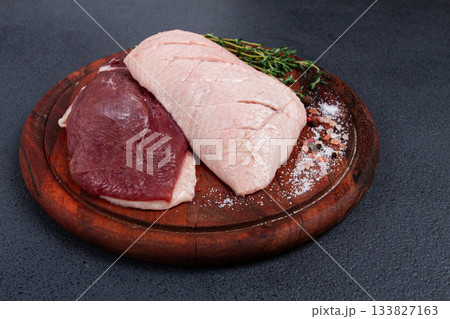 Fresh raw duck breasts, on a wooden chopping board, with herbs and spices, no people 133827163