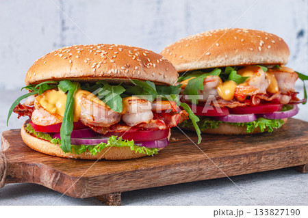 Shrimp burgers with fresh ingredients are served on a wooden board in a bright kitchen, 133827190