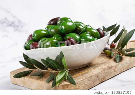 Chalkidiki olives, classic Greek green olives, in a bowl on a cutting board, top view, without people, 133827193