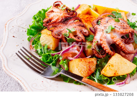 Grilled octopus with baked potatoes and fresh herbs, on a decorative light plate, homemade, no people Grilled octopus with baked potatoes and fresh herbs, on a decorative light plate, homemade, no people 133827208