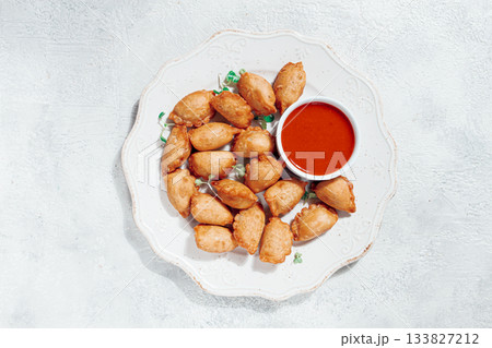 Fried mini chebureks, with sauce, on a decorative plate, hard light, no people, Fried mini chebureks, with sauce, on a decorative plate, hard light, no people, 133827212