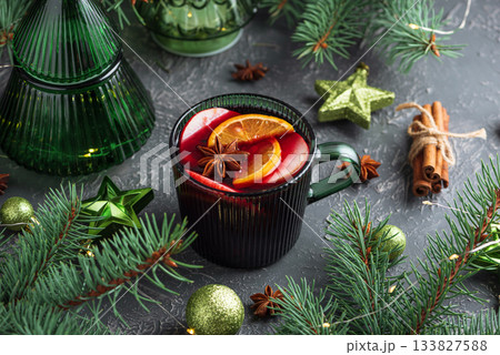 Holiday Mulled Wine with Orange and Apple in Green Mug Surrounded by Christmas Decor 133827588