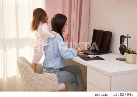 Happy mother hugging daughter during remote work from a home office Happy mother hugging daughter during remote work from a home office 133827843