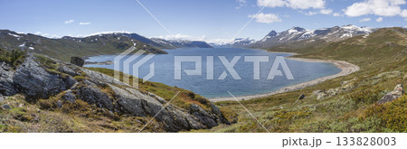 Exploring the serene shores of Lake Bygdin in Jotunheimen National Park on a sunny afternoon 133828003