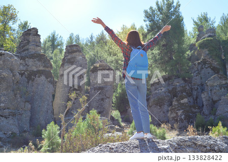 A woman tourist with a backpack on her back walks through the ancient city of Selga, admiring the wonderful nature and wonderful rocks. Turkey, Antalya. A woman tourist with a backpack on her back walks through the ancient city of Selga, admiring the wonderful nature and wonderful rocks. Turkey, Antalya. 133828422