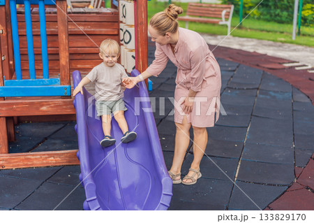A mother playing with her young son at an outdoor playground, enjoying joyful family time and positive parenting moments. Childhood fun, bonding, laughter and carefree early years concept A mother playing with her young son at an outdoor playground, enjoying joyful family time and positive parenting moments. Childhood fun, bonding, laughter and carefree early years concept 133829170
