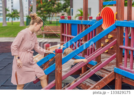 A mother playing with her young son at an outdoor playground, enjoying joyful family time and positive parenting moments. Childhood fun, bonding, laughter and carefree early years concept A mother playing with her young son at an outdoor playground, enjoying joyful family time and positive parenting moments. Childhood fun, bonding, laughter and carefree early years concept 133829175