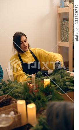 Craftswoman designs sustainable evergreen centerpiece with glowing candles 133829789