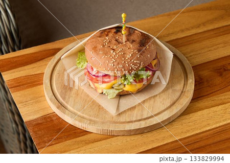Rustic sandwich on natural setting, Traditional beef burger with fresh ingredients displayed Rustic sandwich on natural setting, Traditional beef burger with fresh ingredients displayed 133829994