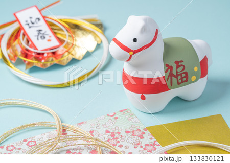 水色背景に置かれた白い馬の置物と迎春飾り 133830121