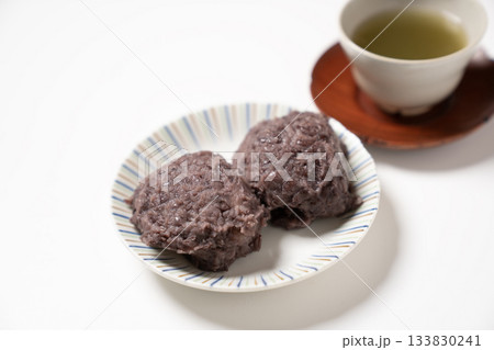 白い皿にのった2つのおはぎとお茶 133830241