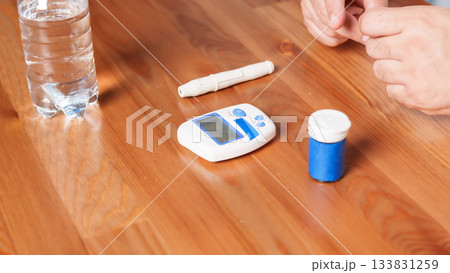 4K close-up of a glucometer lying on a table with diabetes testing accessories. Clean minimalistic setup, soft medical lighting, and a clear healthcare atmosphere. Concept of blood glucose monitoring 133831259