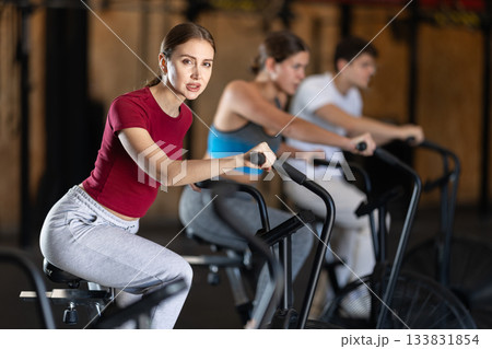 Focused girl works out with airbike during class at fitness club Focused girl works out with airbike during class at fitness club 133831854