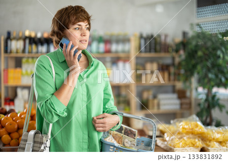 Woman making phone calls in supermarket Woman making phone calls in supermarket 133831892