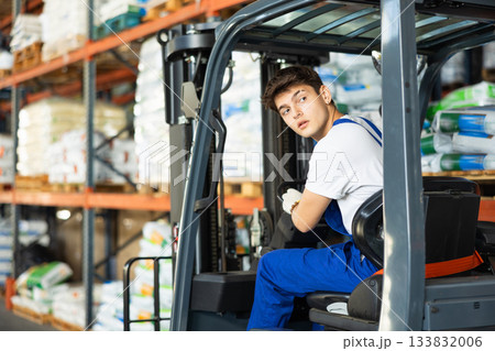 Young guy worker works on loader in warehouse 133832006