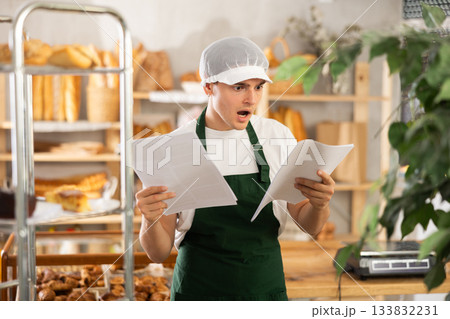 Young baker looking confused while reviewing order documents Young baker looking confused while reviewing order documents 133832231