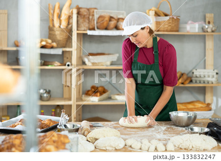 Woman works in bakery as baker, kneads dough, works with flour. Woman works in bakery as baker, kneads dough, works with flour. 133832247