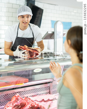 Young male seller offers girl to buy fresh beef entrecote boneless meat Young male seller offers girl to buy fresh beef entrecote boneless meat 133832295
