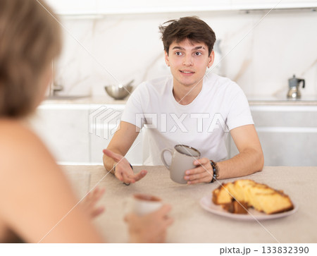 Adult woman and young guy drink tea and talk in kitchen 133832390