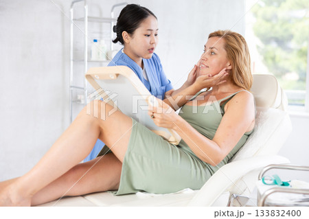 Professional cosmetologist talking about anti-aging skincare to patient Professional cosmetologist talking about anti-aging skincare to patient 133832400