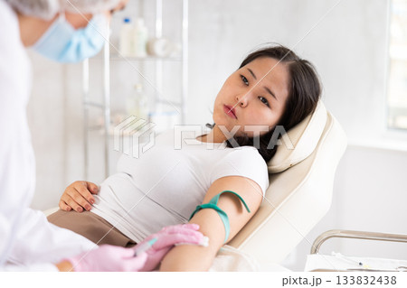 Middle-aged doctor giving injection into vein Middle-aged doctor giving injection into vein 133832438