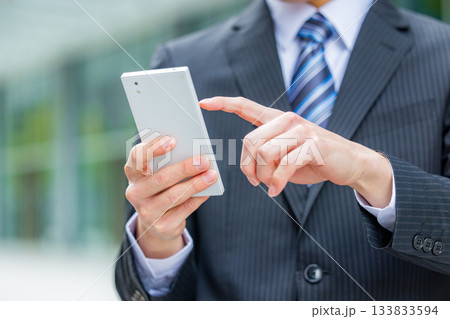 オフィスでスマホを操作する若いビジネスマンの手元 133833594