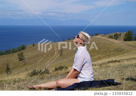 A girl rests at the peak of a mountain after climbing A girl rests at the peak of a mountain after climbing 133833812