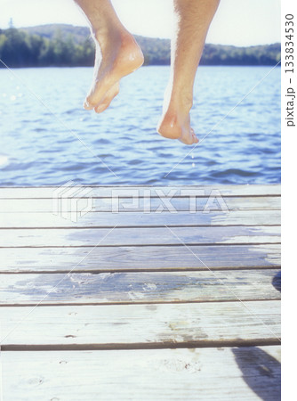 Legs of man jumping off dock into lake Legs of man jumping off dock into lake 133834530