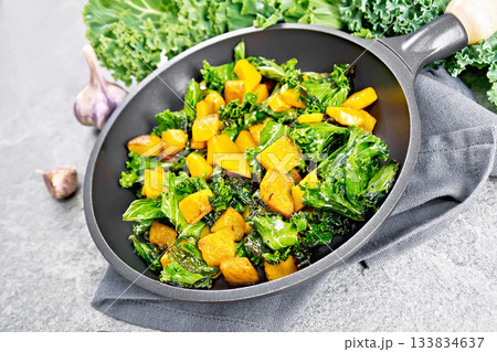 Kale with pumpkin in skillet on granite table 133834637