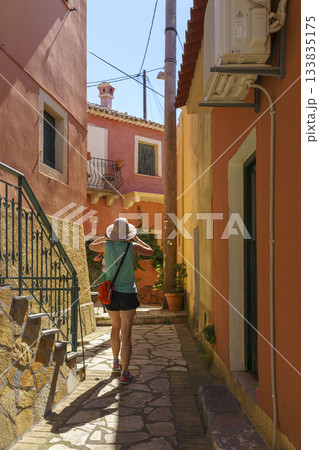 Rear view of woman walking down narrow cobblestone alley 133835175