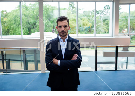 Male business professional standing in modern lobby near glass railing and floor-to-ceiling windows 133836569