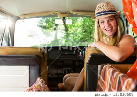 Woman leaning over driver seat in campervan wearing straw hat and polka dot blouse, copy space Woman leaning over driver seat in campervan wearing straw hat and polka dot blouse, copy space 133836609