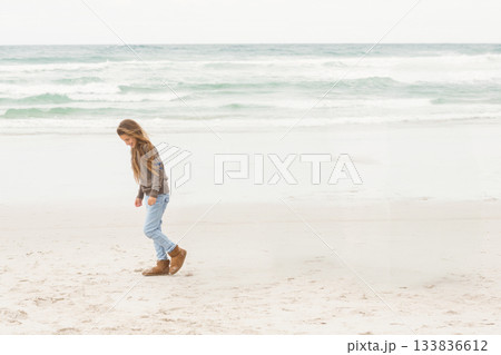 Child girl walking on sandy beach leaving footprints in wet sand near calm waves, copy space 133836612