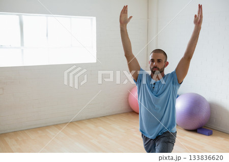 30s man performing lunge pose on wooden floor in exercise room with stability balls, copy space 30s man performing lunge pose on wooden floor in exercise room with stability balls, copy space 133836620