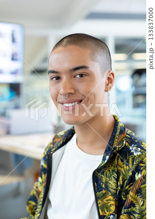 Man wearing botanical print jacket working at office desk with desktop monitor and glass partition 133837000