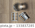 Glass of water with pill blister packs 133837285