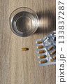Glass of water with pill blister packs 133837287