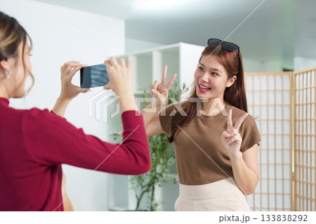 Capturing Memories. Young woman posing for a selfie while her friend takes a photo. Capturing Memories. Young woman posing for a selfie while her friend takes a photo. 133838292