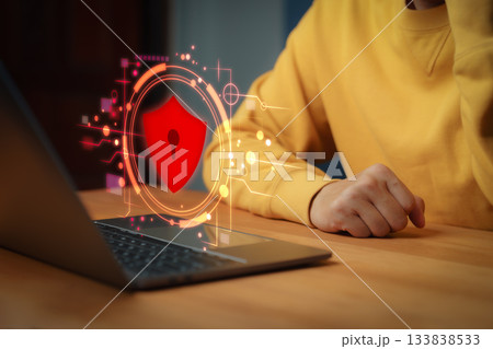 Person using laptop computer with glowing red security shield hologram, symbolizing cybersecurity, data protection, privacy, firewall, encryption, and online safety. Person using laptop computer with glowing red security shield hologram, symbolizing cybersecurity, data protection, privacy, firewall, encryption, and online safety. 133838533