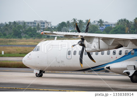 Regional turboprop aircraft taxiing on the runway with propeller visible 133838914
