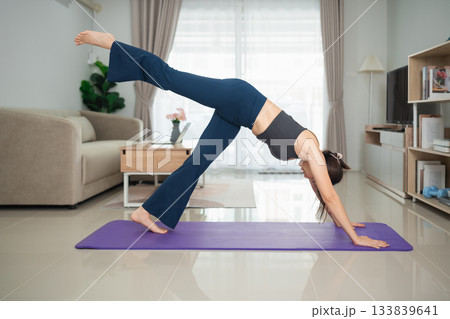 Woman Practicing Yoga Pose in Living Room with Relaxing Atmosphere and Modern Decor, Focused on Physical Fitness and Wellness Lifestyle 133839641