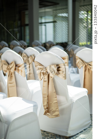 Vertical view of wedding chairs with beautiful gold satin bows 133840042