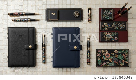 Luxury fountain pen collection with leather notebooks and decorative Japanese lacquer ink stone sets arranged on marble surface 133840348
