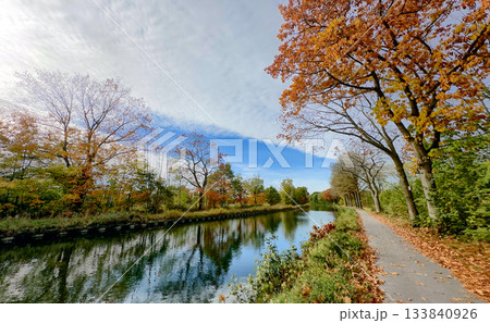 Crisp air and amber leaves beside calm reflective water 133840926