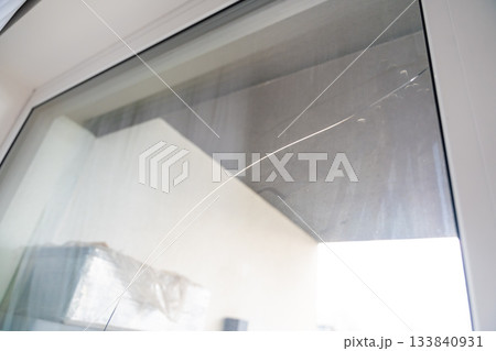 Large crack across a triple glazed window in a residential apartment. Indicates potential structural issues, thermal stress or manufacturing defect during construction. 133840931