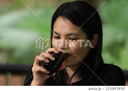 Young Asian woman drinking coffee in a restaurant in Thailand. Young Asian woman drinking coffee in a restaurant in Thailand. 133841650